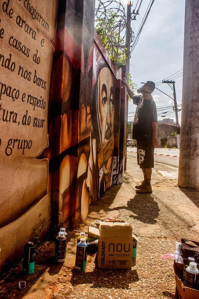 artista atuando sobre um grafite, que ele está restaurando