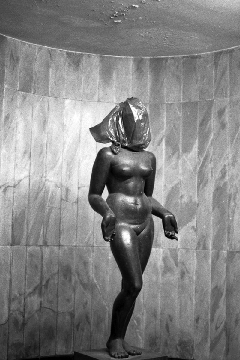 A imagem mostra uma estátua de uma mulher nua com saco em sua cabeça.