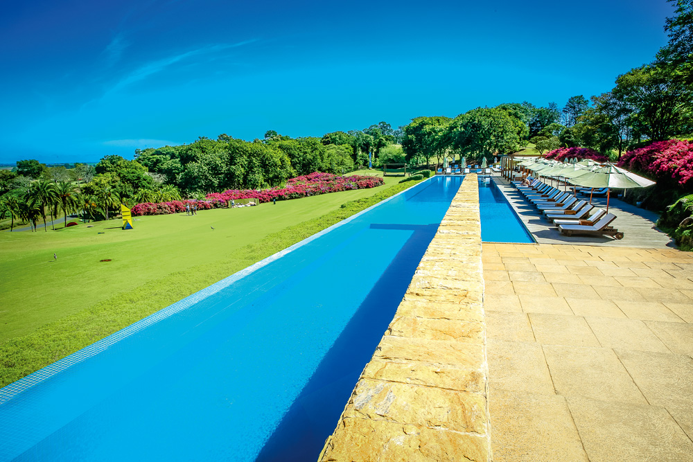 A imagem é de uma paisagem da piscina da Fazenda Boa Vista, com uma extensão comprida, céu azul e muitas áreas verdes no entorno