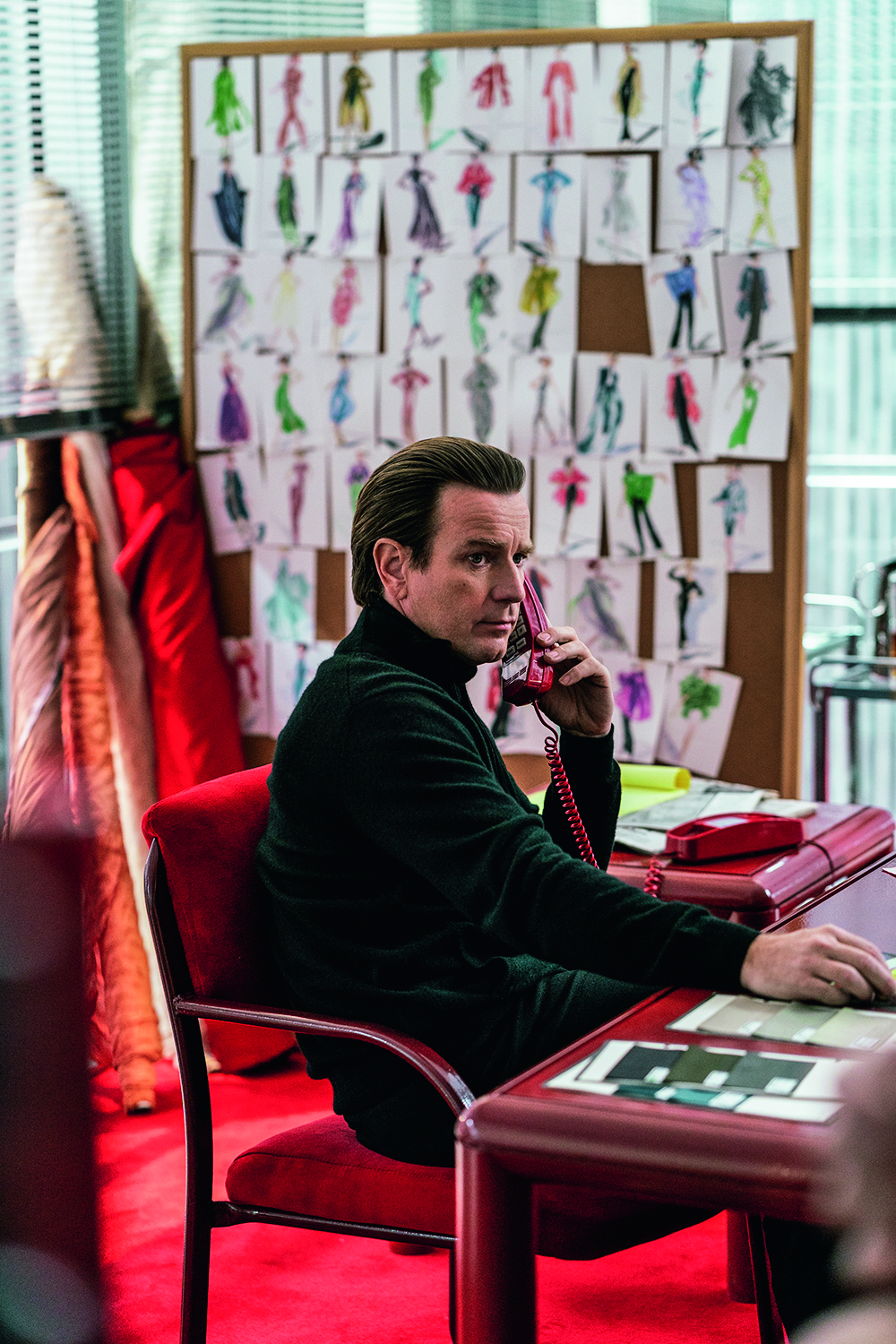 A imagem mostra Ewan McGregor, fantasiado como o personagem sentado em uma cadeira vermelha falando no telefone