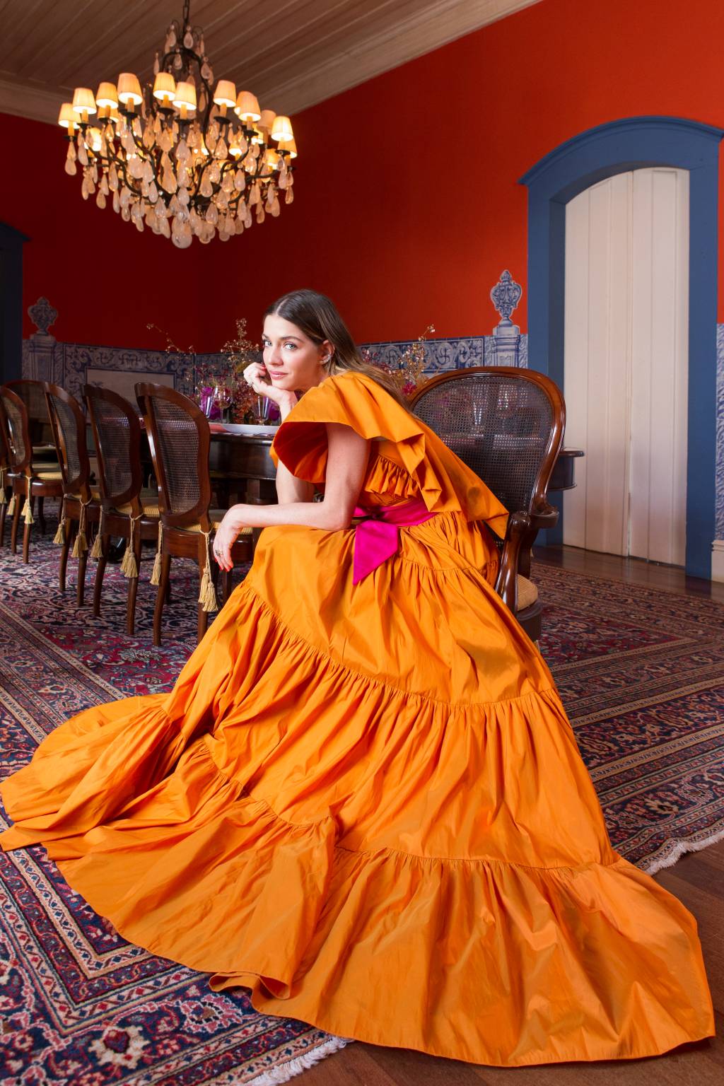 Luma Costa posa sentada com grande vestido laranja espalhado pelo chão.