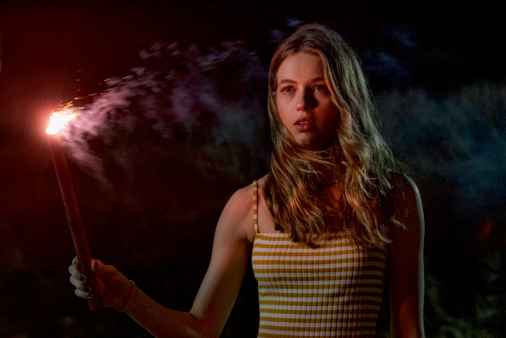 A imagem mostra Olivia Welch segurando um sinalizador durante cena do filme Panic