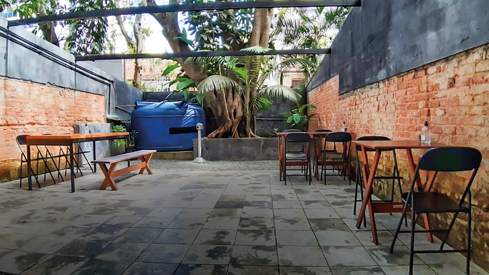 Na imagem é mostrado o quintal do bar Boca de Ouro. Com mesas tendo um distanciamento social.