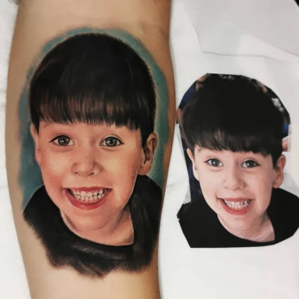 Um braço com uma tatuagem de uma criança sorrindo, ao lado uma foto recortada desta tatuagem