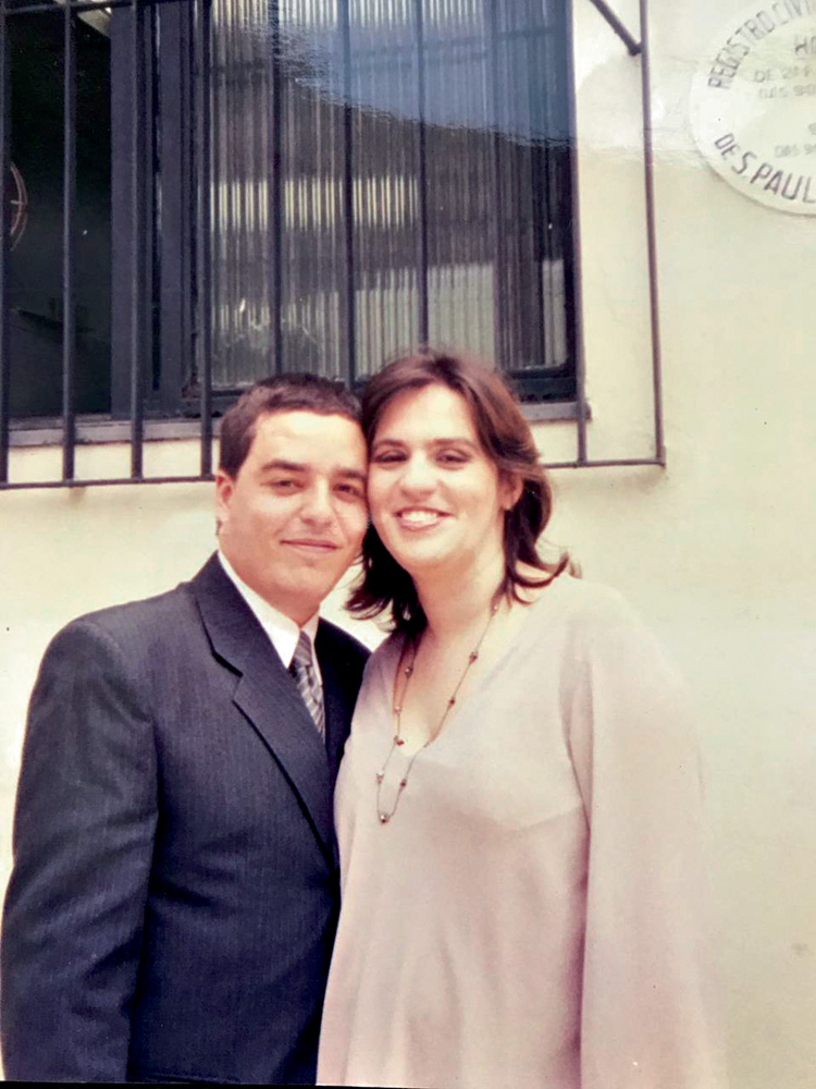 luciano e adriana sorriem para a foto, com roupas sociais, na ocasião do seu casamento no civil