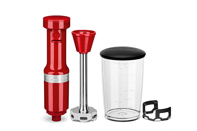 Imagem com fundo branco do mixer vermelho da KitchenAid junto de copo de acrílico e um protetor de cor preta para a lâmina.