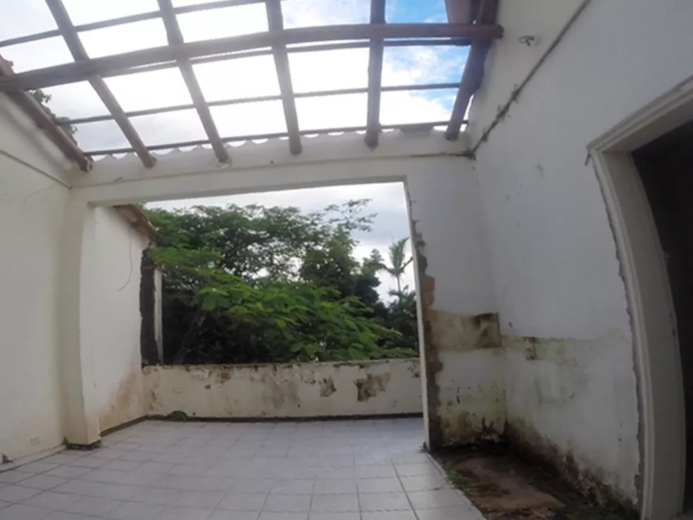 casa1 Interior de uma casa, com vão aberto para árvores, tem mofo nas paredes