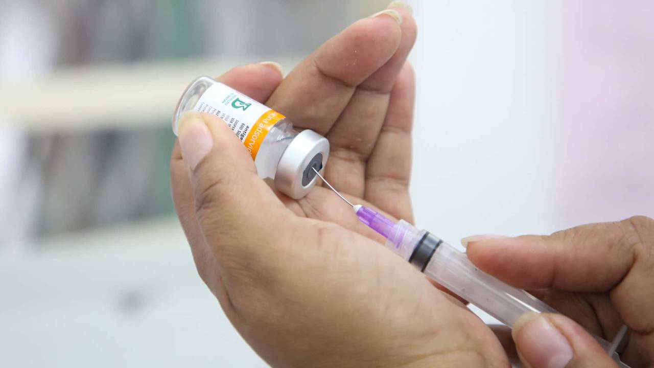 Imagem mostra enfermeira retirando dose de vacina de frasco com seringa