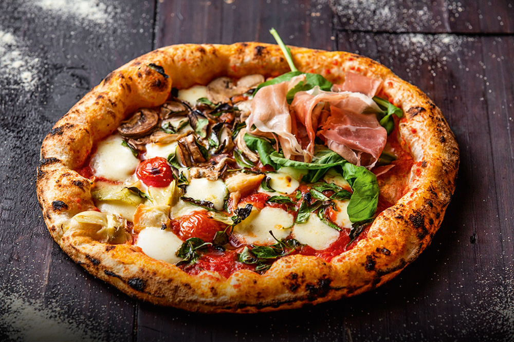 Pizza individual da Pizza da Mooca chamada quatro estações (funghi, margherita, parma e alcachofra).