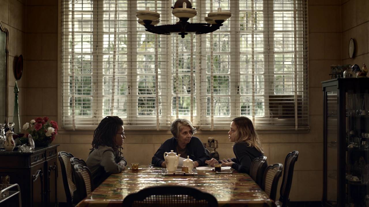 Três mulheres em uma mesa conversam entre si