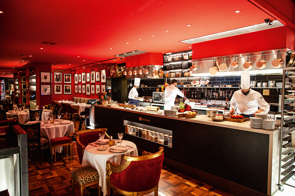 Restaurante com paredes vermelhas, balcão de bar e mesas