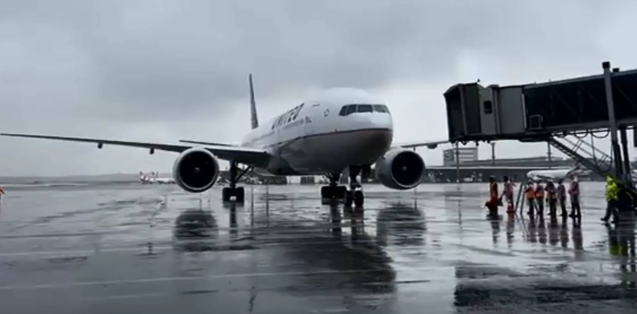 A imagem mostra um avião pousando no aeroporto de Guarulhos durante um tempo nublado