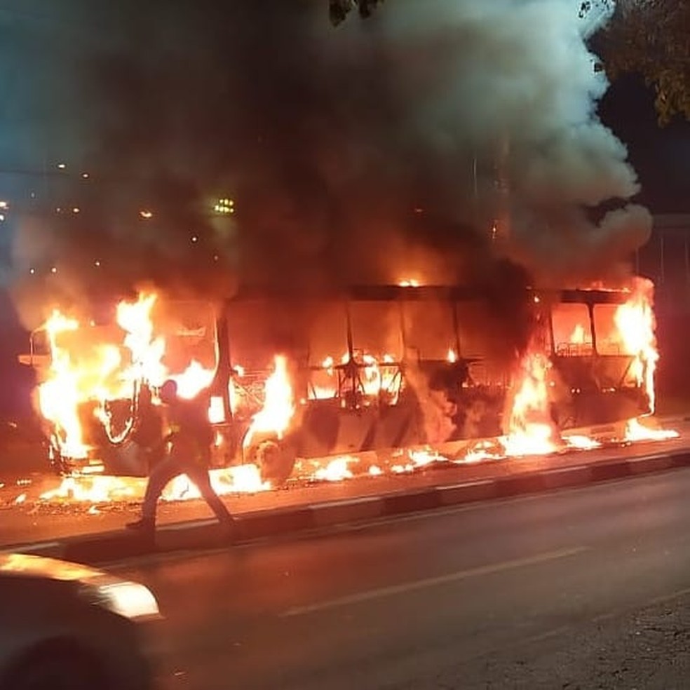 Foto exibe ônibus pegando fogo na rua.