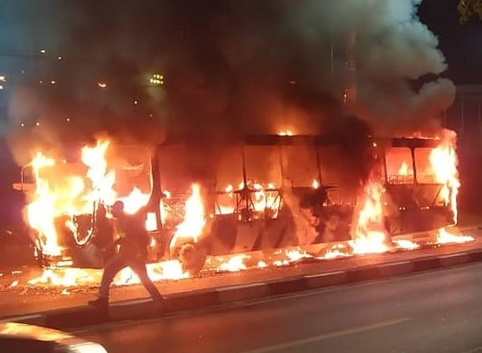 Foto exibe ônibus pegando fogo na rua.