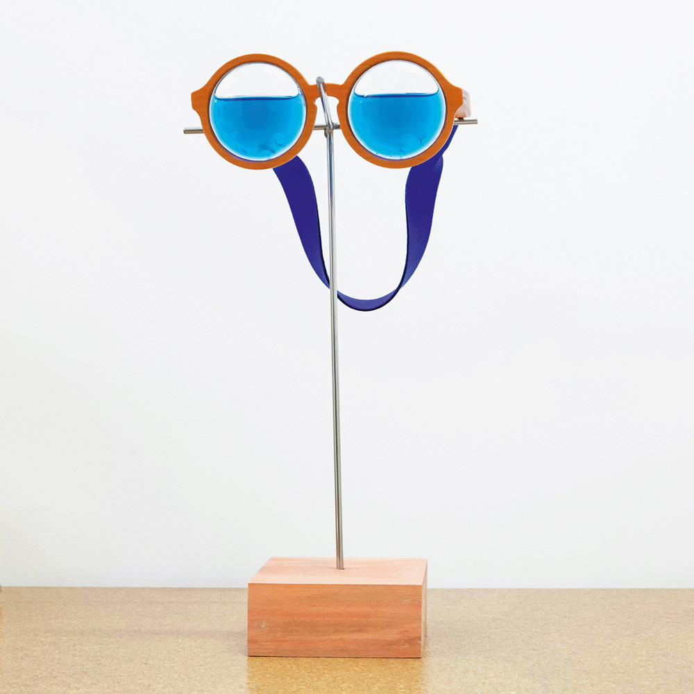 Crédito_Mariane klettenhofer.jpeg Foto mostra uma obra em cima de uma mesa, que é um óculos com água nas lentes