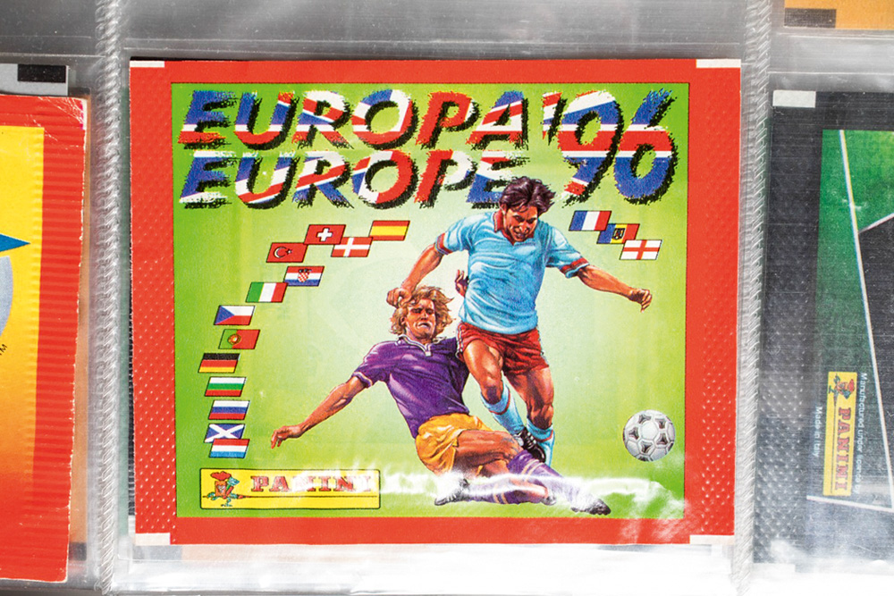 A imagem mostra o envelope de um pacotinho de 1996, do álbum da Eurocopa.