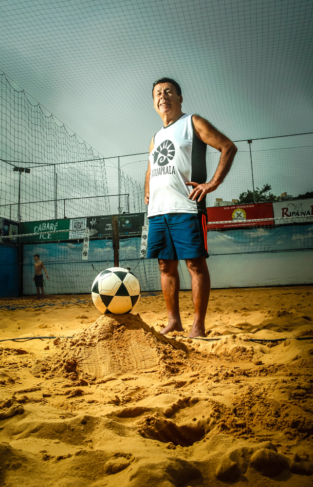 A imagem mostra Torralbo em uma quadra de futevôlei, com a bola posicionada em sua frente sobre um montinho de areia.