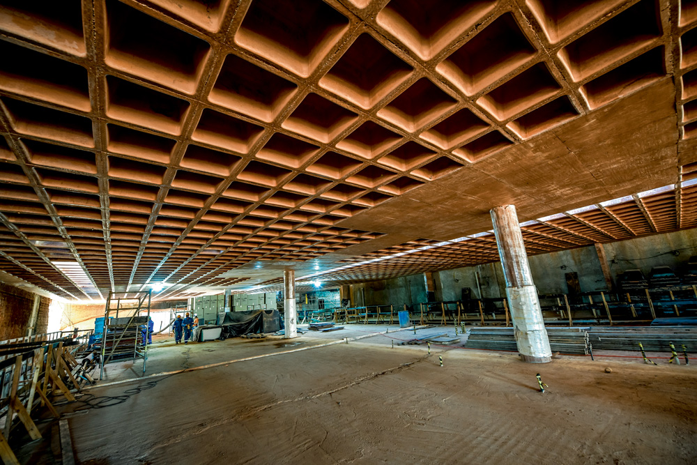 A imagem mostra um andar vazio do Museu do Ipiranga. No teto, é possível ver o formato de grelha, sendo ele inteiro quadriculado com buracos quadrados.