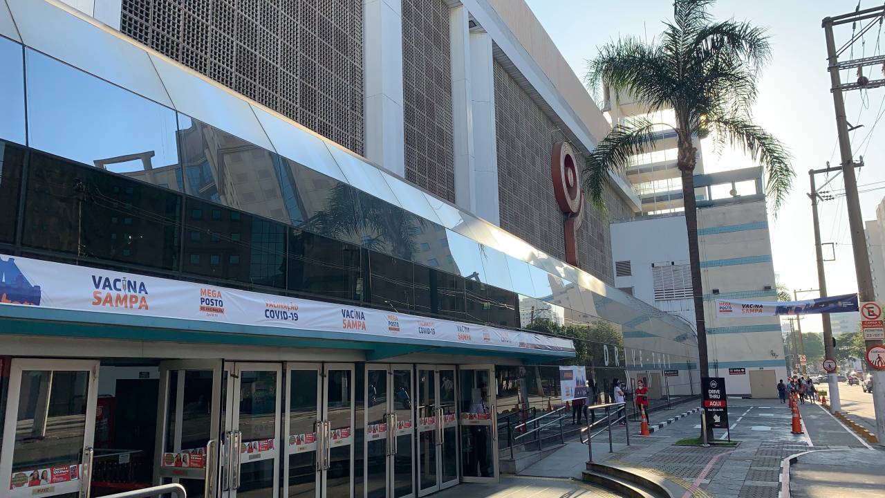 A imagem mostra a fachada do Shopping Ibirapuera com um banner discreto escrito "Vacina Sampa"