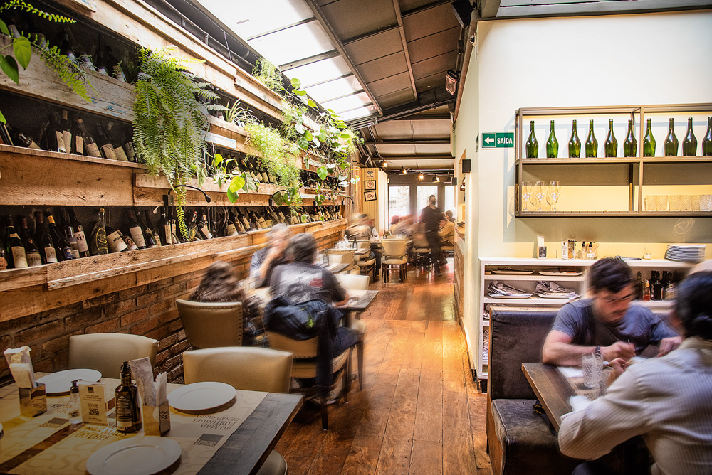 Salão do restaurante Tasca da Esquina, com mesas e parade de plantas à esquerda.