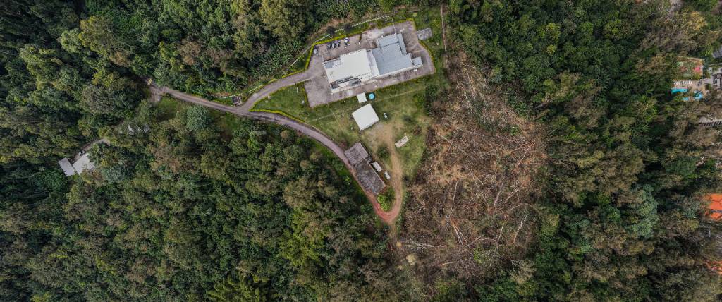 Imagem aérea mostra região coberta de mata, com edificação ao centro e, ao lado, área com árvores caídas no chão