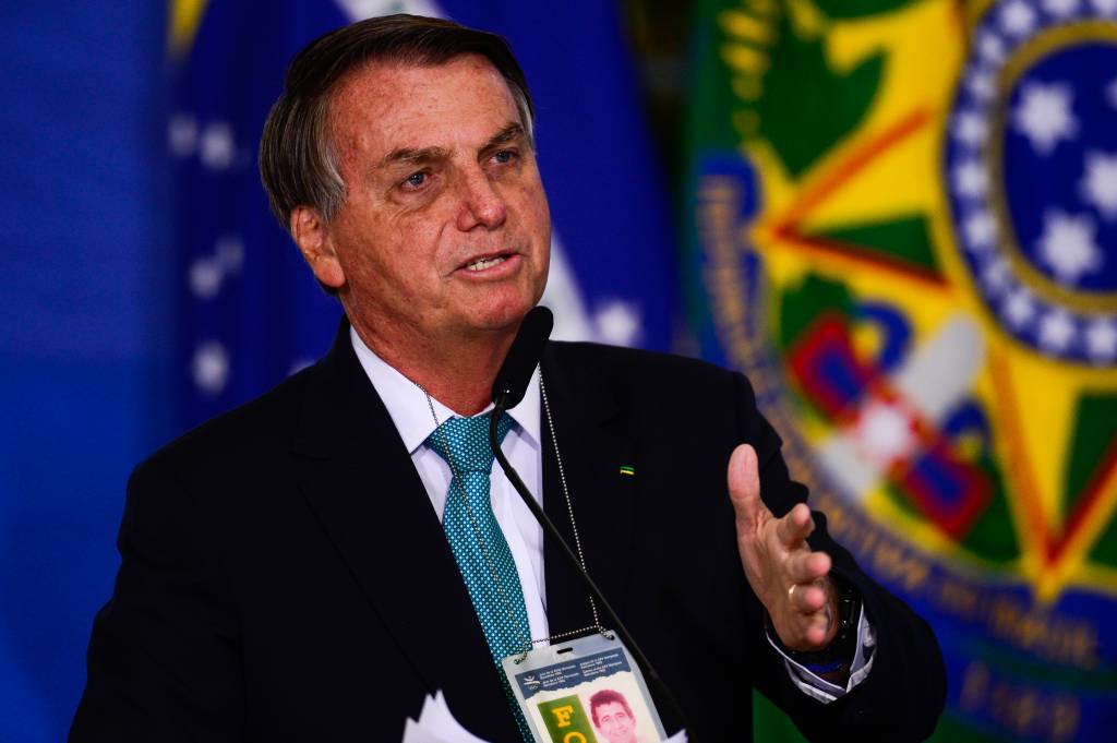 Jair Bolsonaro aparece durante cerimônia, usando terno e gravata, discursando diante de microfone