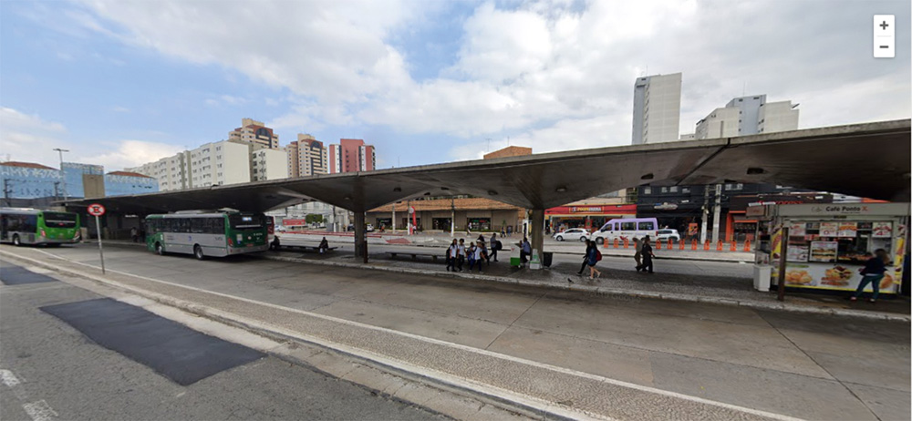 Foto mostra terminal de ônibus do Ana Rosa. Tem pessoas esperando ônibus