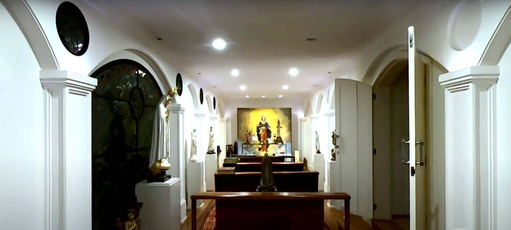 os bancos da capela no centro, o altar ao fundo e as paredes que cercam a capela com estátuas sacras