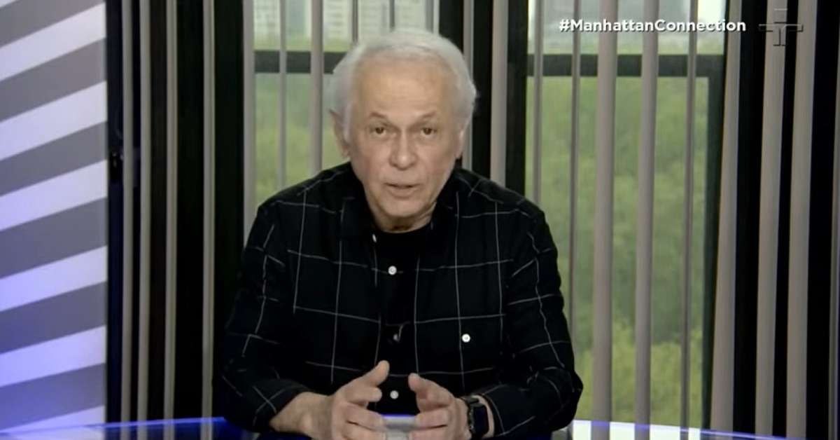 Imagem mostra Lucas Mendes no estúdio do programa, usando blazer