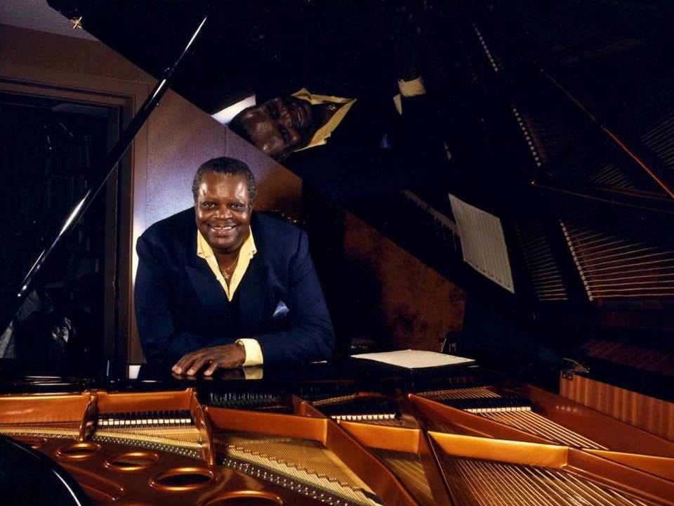 Homem negro apoiado em piano