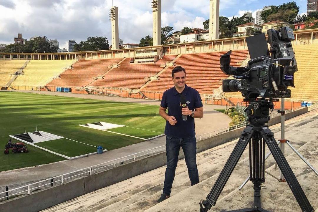 A imagem mostra o repórter Chico Garcia, da Band, durante entrevista em um estádio de futebol