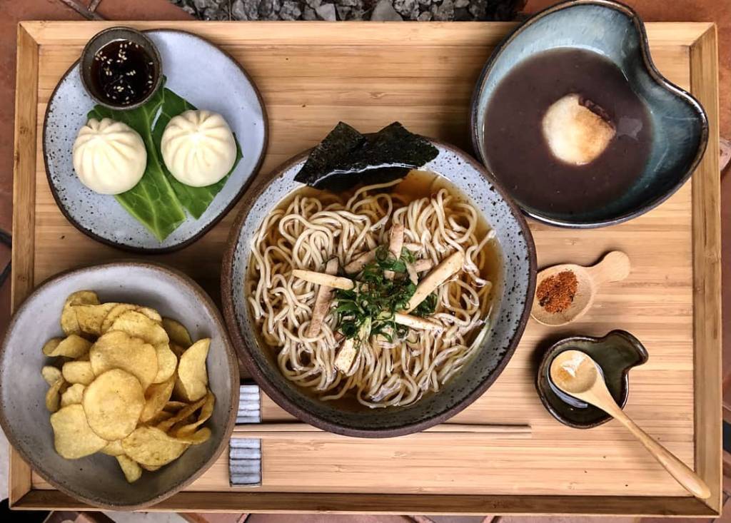 Foto aérea de mesa de madeira com potes de cerâmica com receitas preparadas pela chef Telma Shiraishi.