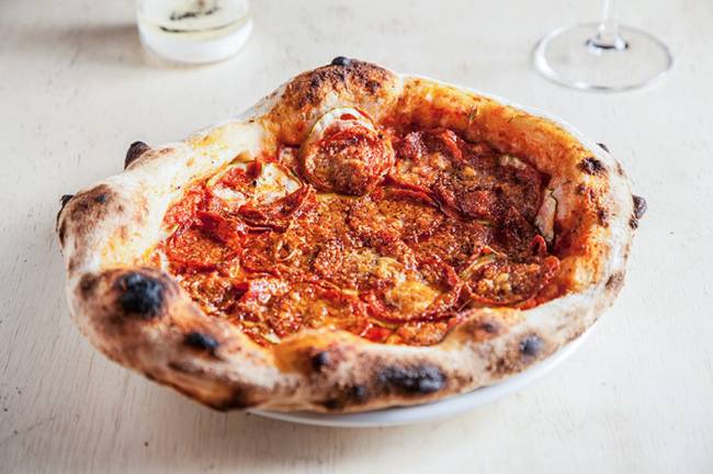 Dia da Pizza – Bocada’s Pizza de pepperoni sobre bancada branca.