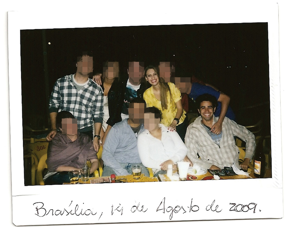 A imagem mostra Carol em pé e Tiago sentado em uma mesa de bar. Há várias outras pessoas em volta e os dois estão relativamente longe um do outro.