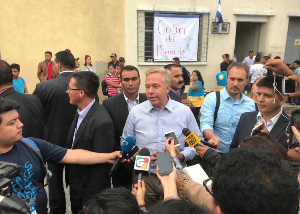 Americano David Hodge em entrevista a jornalistas na Guatemala. Aparece rodeado por repórteres segurando microfones. Veste camisa azul clara.