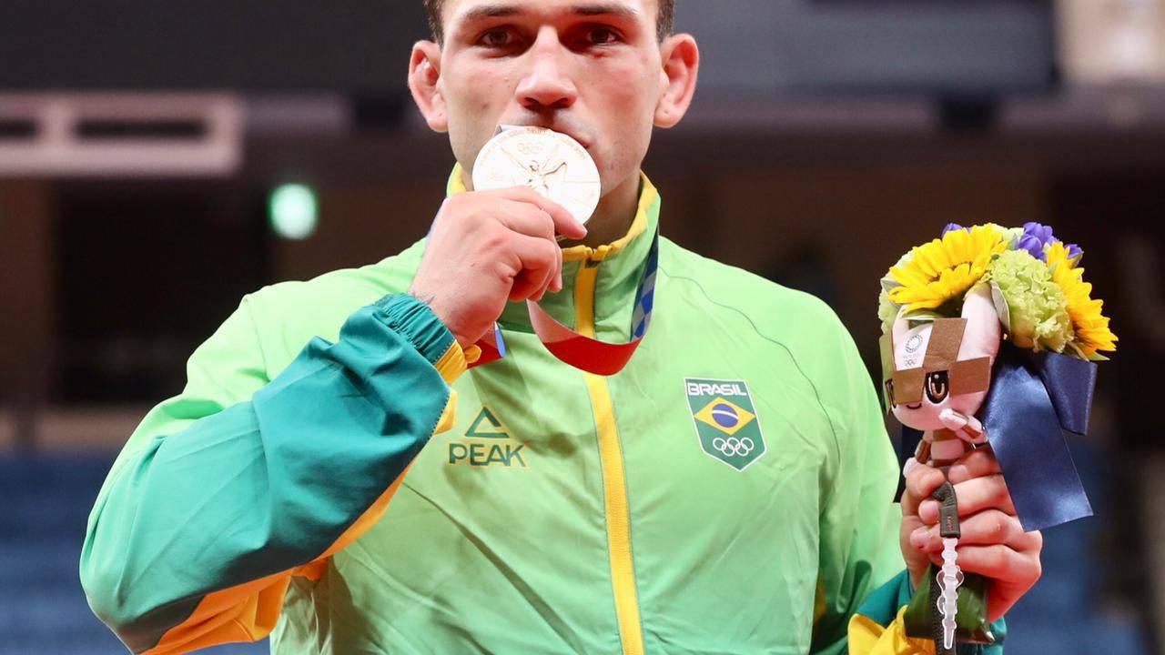 A foto mostra o atleta Daniel Cargnin beijando sua medalha de bronze