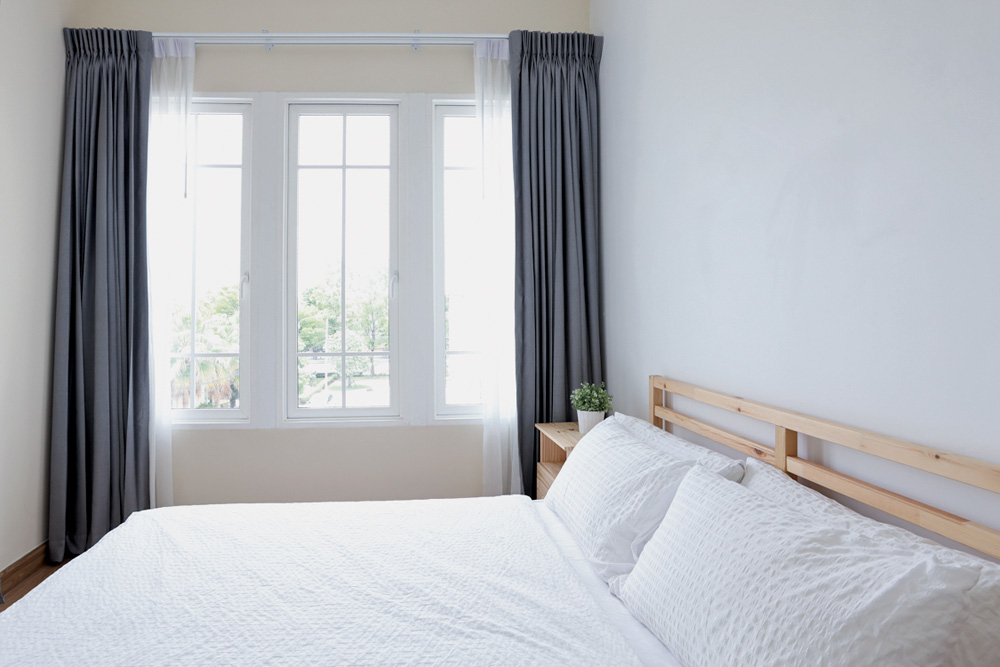 Vista lateral de uma cama de madeira branca moderna em quarto branco com luz suave e clara