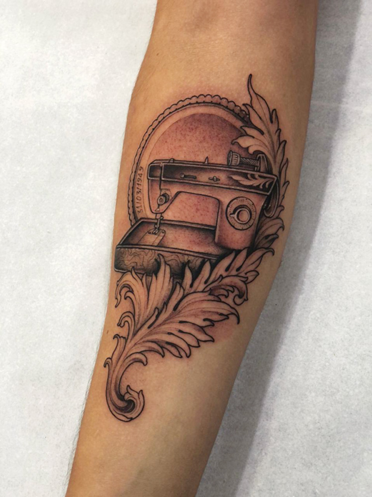 foto do braço de guilherme, com o desenho de uma máquina de costura tatuado em seu braço