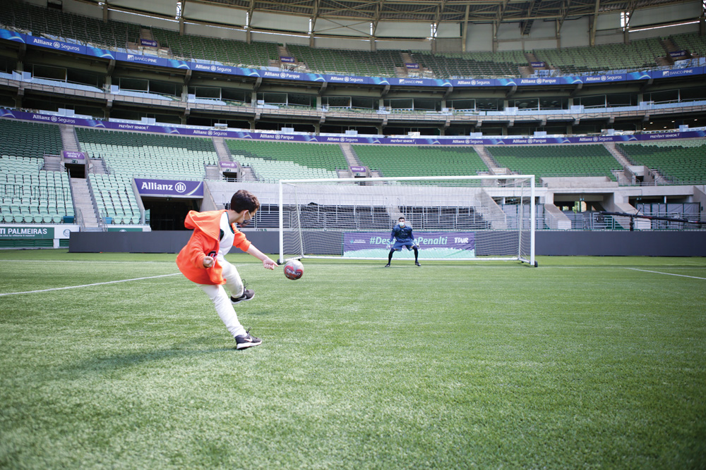 No estádio Allianz Parque, foto capta um menino batendo um pênalti. Estádio está vazio, só tem o menino e o goleiro