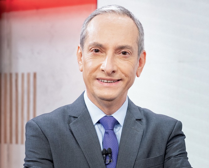 José Roberto Burnier sorri para a câmera. Veste terno cinza-escuro com gravata azul e cabelo grisalho penteado.