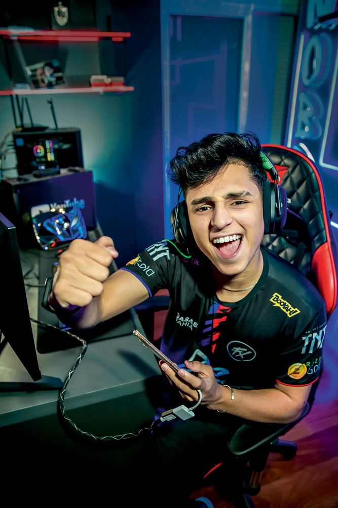 A imagem mostra Bruno "Nobru" Goes sentado em uma cadeira gamer, com uniforme e comemorando para a câmera.