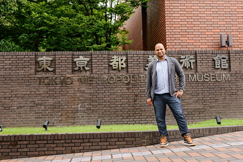 sancler posando para a foto à frente de parede do museu de tóquio com o nome da instituição