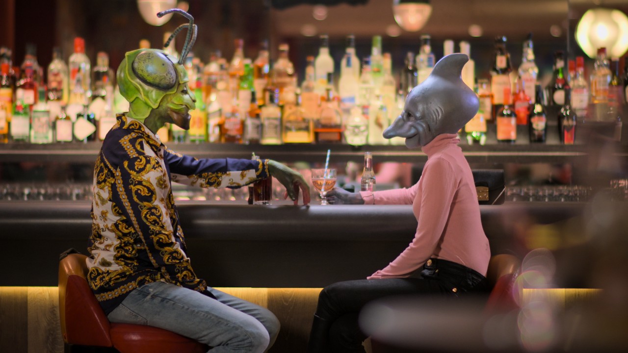 Na foto, duas pessoas fantasiadas se encontram em bar