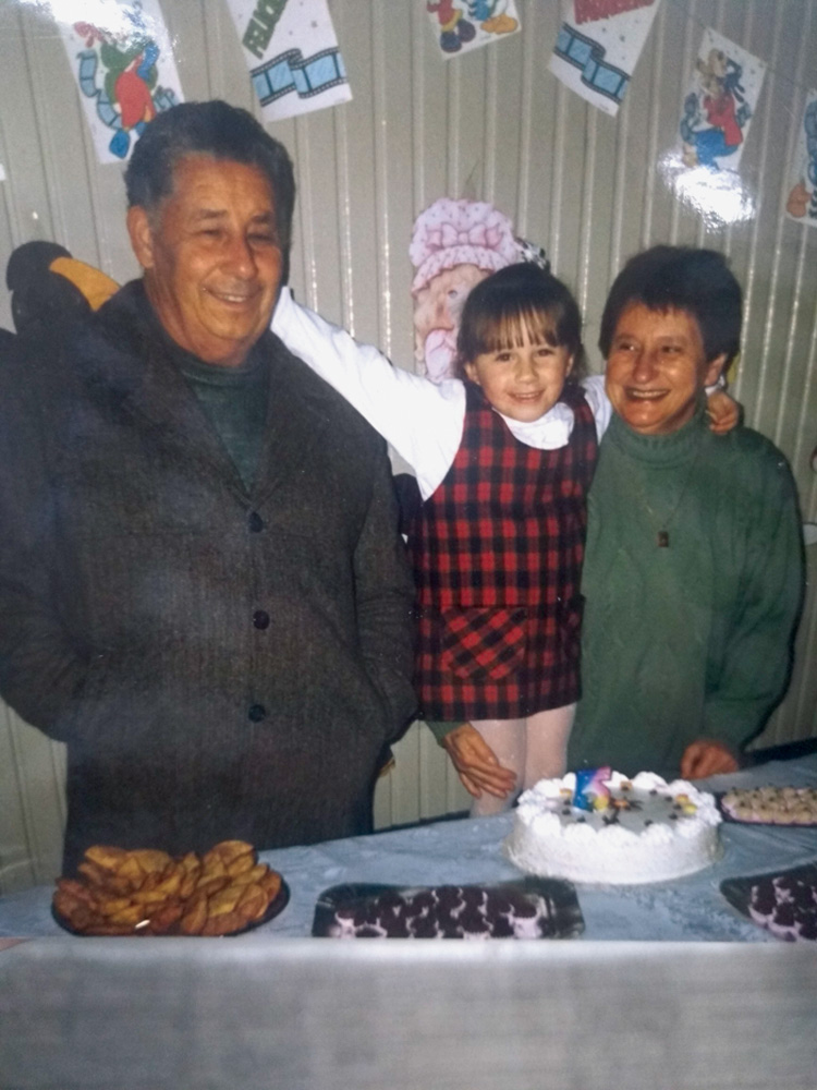 thais abraçada com os avôs José e Zilda, em sua festa de aniversário de 5 anos. à frente deles, uma mesa com bolo e docinhos