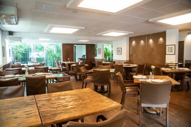 Salão do restaurante Varanda Grill, com mesas de madeira e cadeiras de couro caramelo.