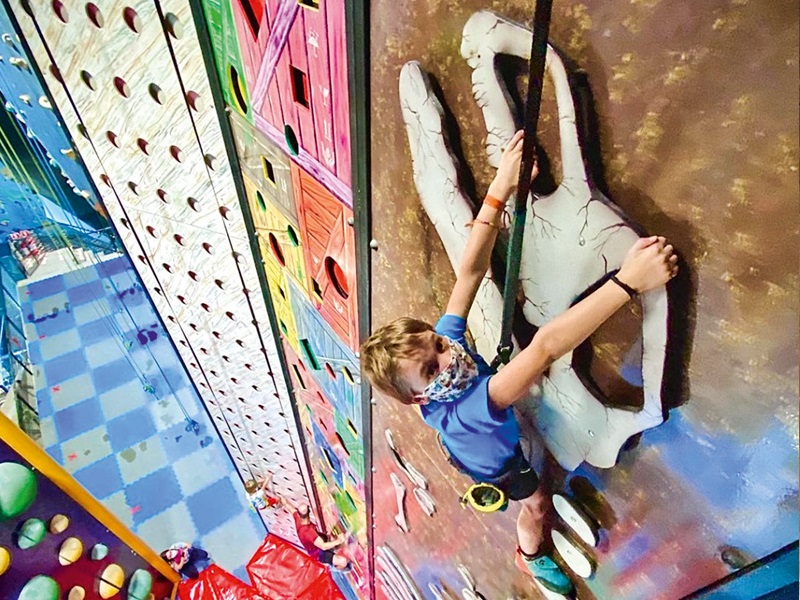 Criança pendurada em cordas escala obstáculos em parede recreativa