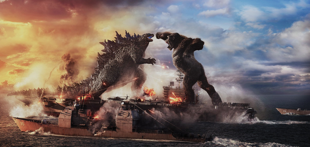 A imagem mostra uma cena de divulgação do filme, com Godzilla e King Kong gritando um com outro, rosto a rosto