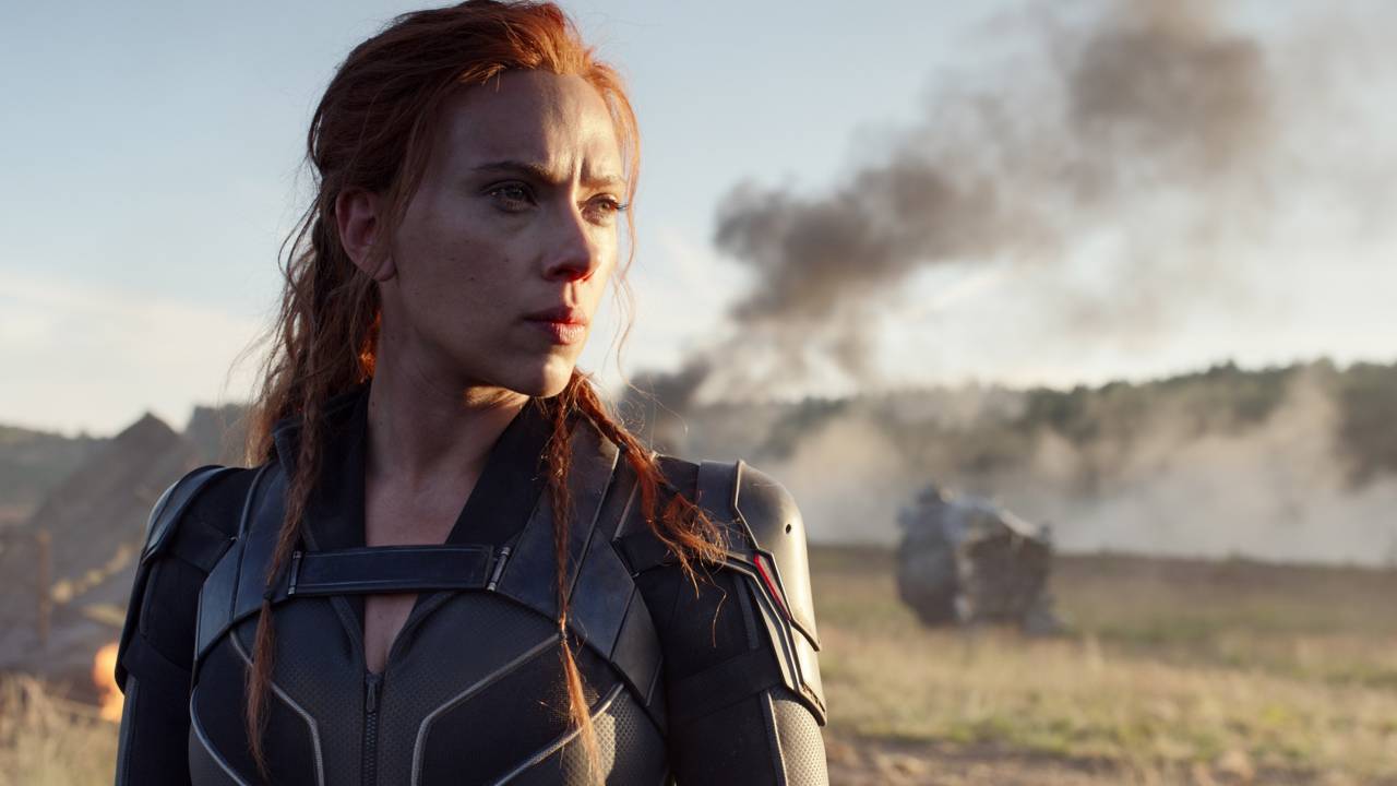 Scarlett Johansson olhando para o canto da tela, em um cenário de guerra