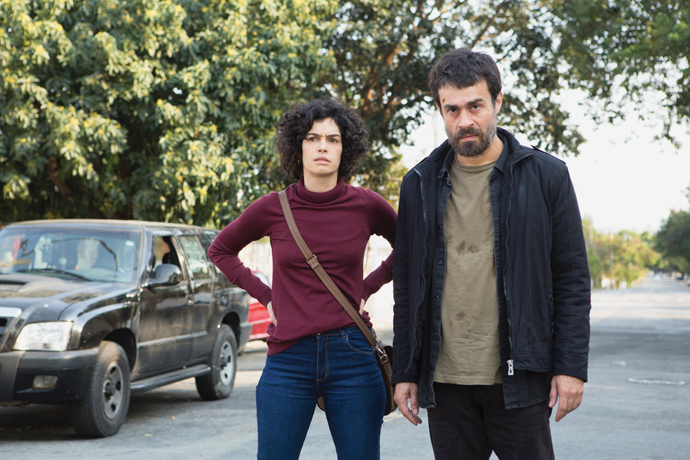 A imagem mostra Maria e Erom em uma rua, os dois olhando sério para frente em cena da série Os Ausentes