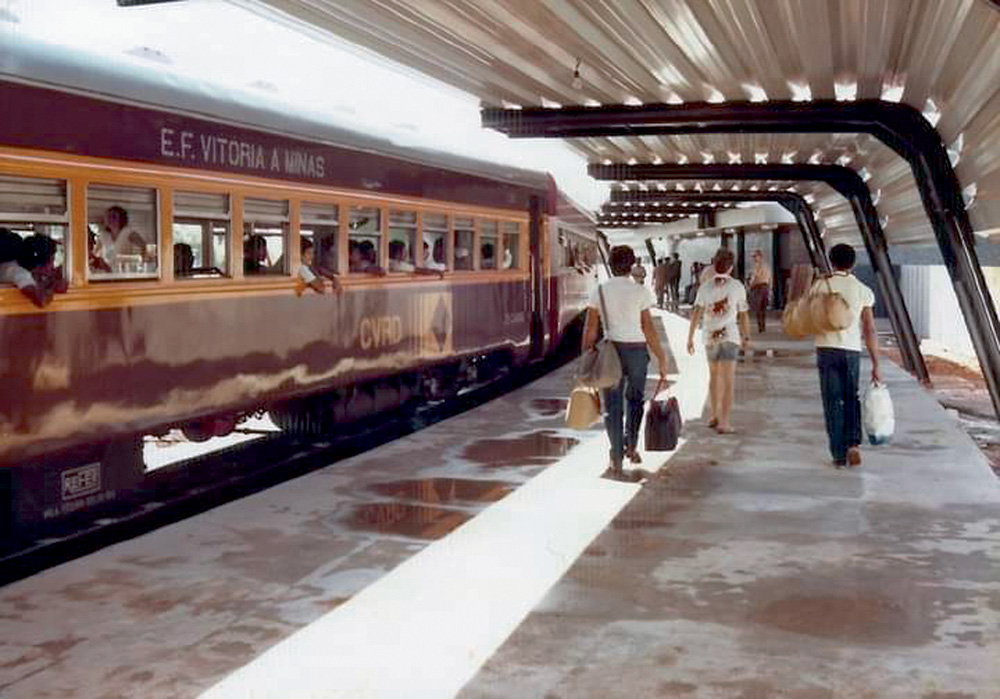 Vagão que circulava de Vitória a Belo Horizonte aparece em foto de arquivo. Suas cores são amarelo e vinho. O vagão está parado e alguns passageiros circulam à direita na plataforma da estação.